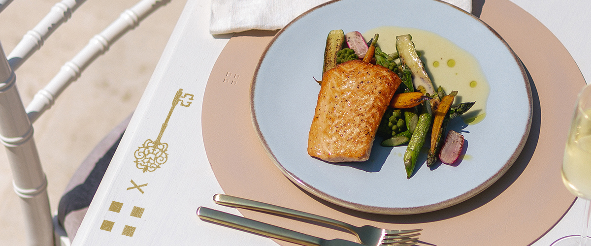 Saumon grillé avec des légumes, servi sur une assiette posée sur une table dressée 