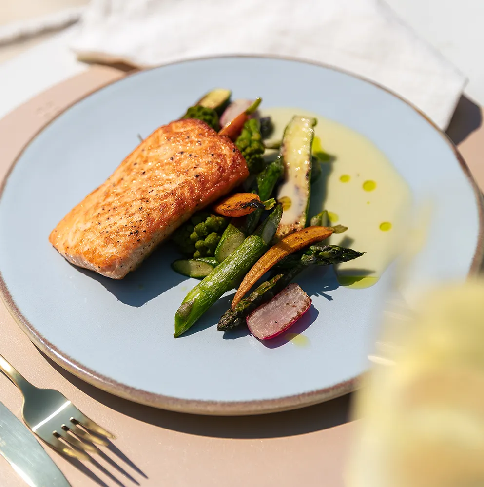 Saumon avec légumes grillés servi dans une assiette bleu clair 